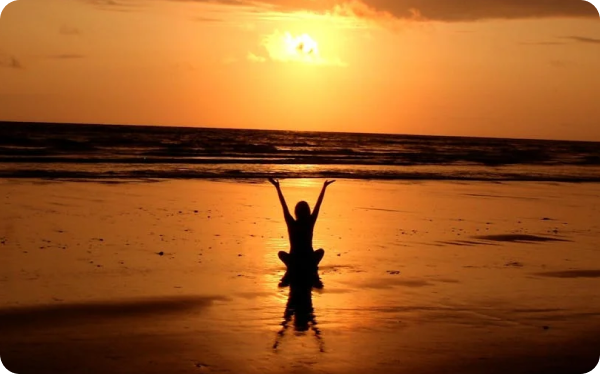 Person relaxing on beach in sunset